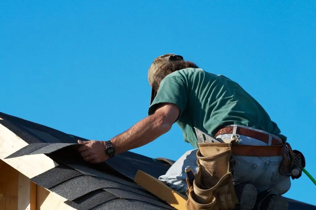 Roofer laying shingles during a roofing repair