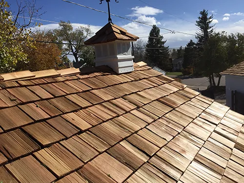 Cedar shake roof with a decorative white cupola against a fall sky