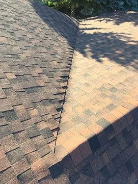 Close-up of asphalt shingle ridge cap installation along a roofline