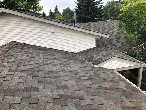 Overhead view of a completed asphalt shingle roof replacement with multiple gables and vents