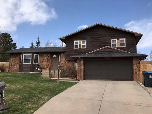 Split-level home with dark wood siding, stone accents, and a matching garage door