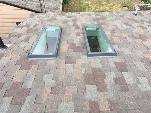 Two rectangular skylights installed flush into an asphalt shingle roof